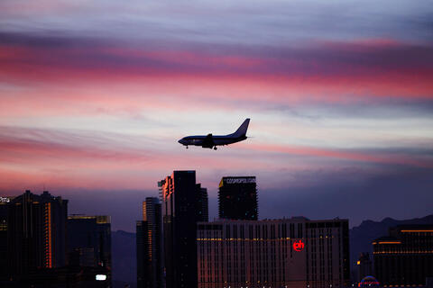 At sunset, an airplane in mid air with the Las Vegas strip in the background