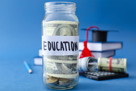 A jar with a hundred dollar bill inside and a label on the jar that says &quot;education&quot;